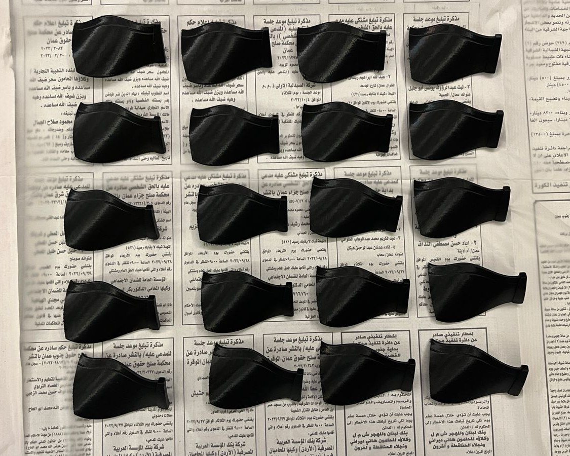 Black printed fan blades laid out in rows on newspaper, before painting.