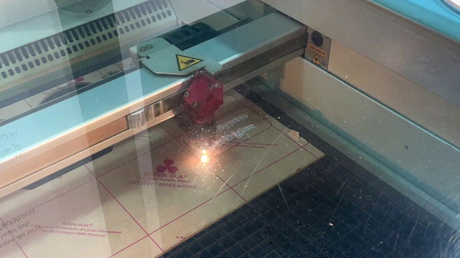The laser cutter engraving the plaque through its viewing window.