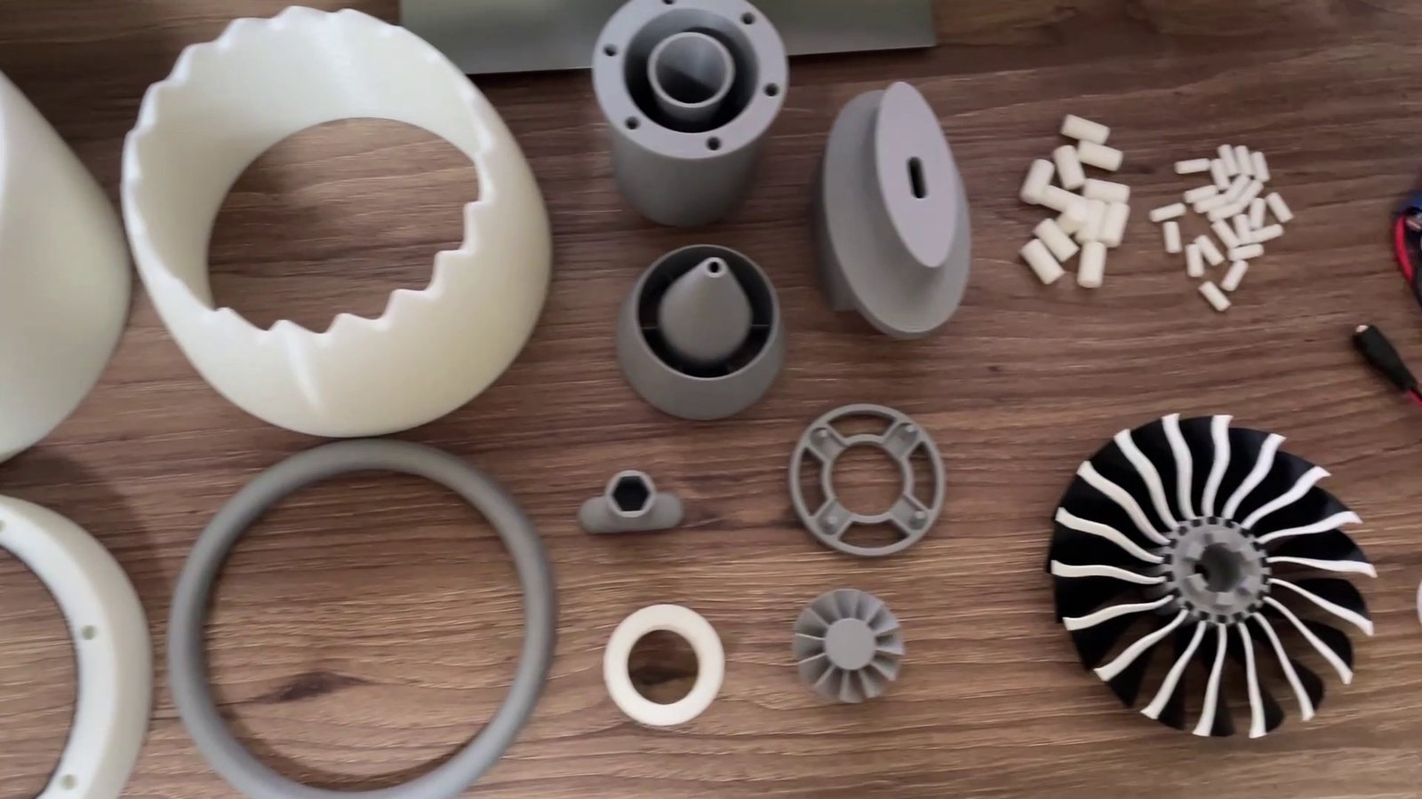 The printed parts laid out before assembly: nacelle sections, exhaust parts, rings, loose pins and the fan.