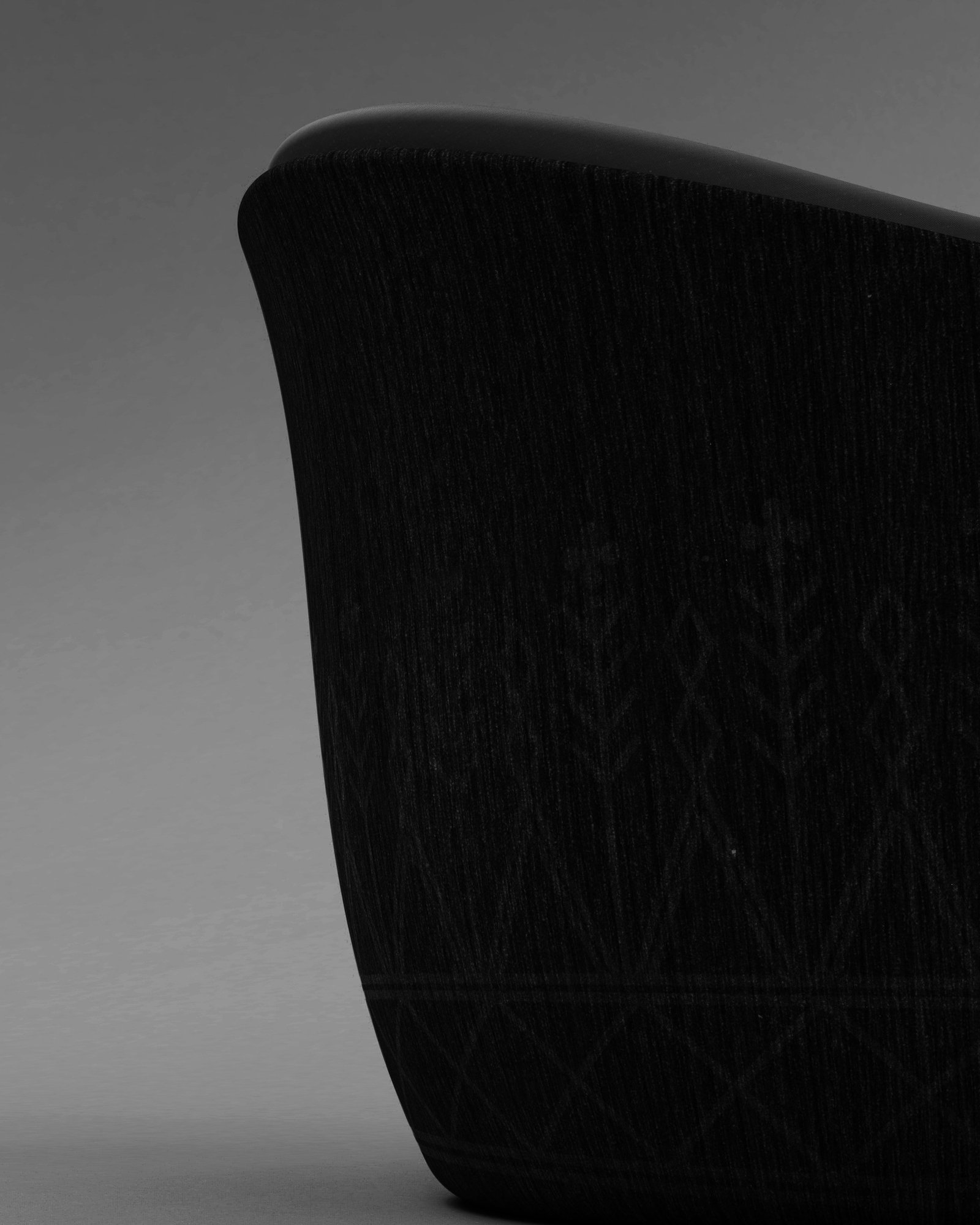 Dark monochrome close-up render of the shell rim, with the engraved branch and triangle pattern faint on the wood grain.