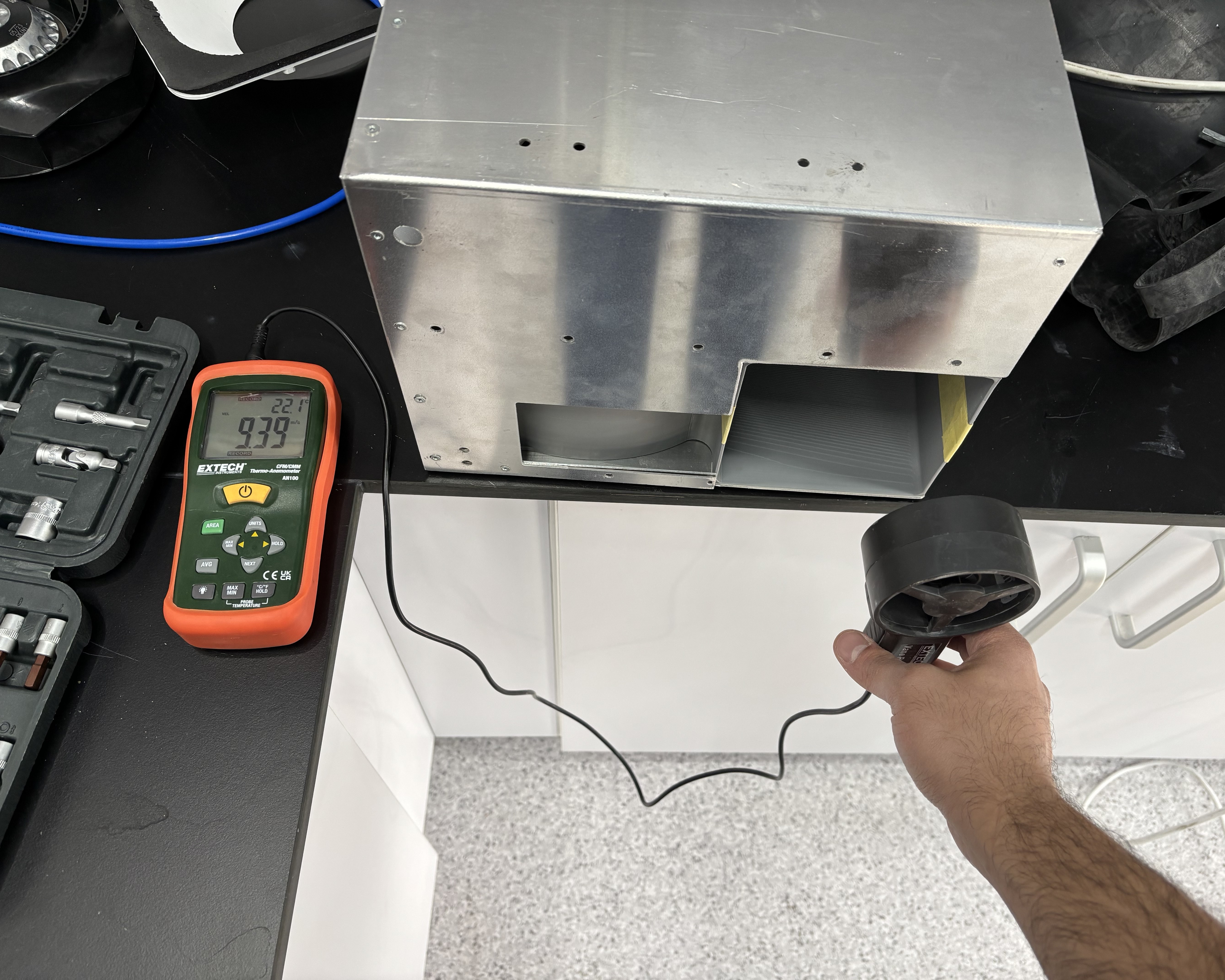 Measuring outlet air velocity on the bench with an anemometer.